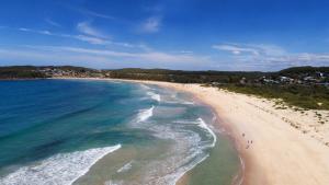 una vista aerea di una spiaggia con persone di Seaside Holiday Resort a Fingal Bay