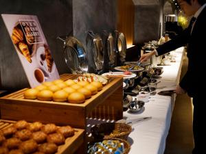 a buffet line with plates of food and a person preparing food at Gardens Cabin in Sapporo