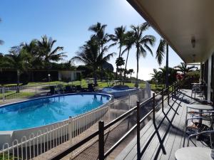 a balcony with a swimming pool and palm trees at Whitsunday Sands Resort in Bowen