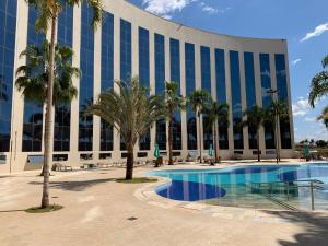 a large building with palm trees and a swimming pool at Barretos Park Hotel - Condo Hotel in Barretos