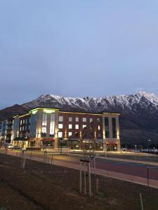 a large building with snow covered mountains in the background at Wyndham Garden Queenstown in Queenstown