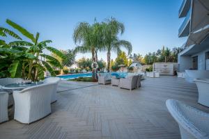 a resort patio with white chairs and a pool at Splendor Hotel in Dhërmi