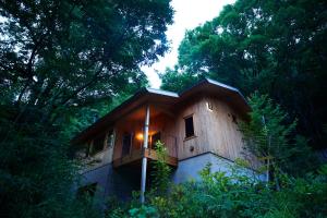a wooden house with a balcony in the woods at Hakone Retreat villa 1f in Hakone
