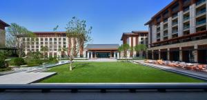 a courtyard in a building with a lawn and chairs at Hyatt Regency Beijing Shiyuan in Yanqing