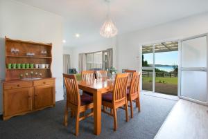 uma sala de jantar com uma mesa de madeira e cadeiras em Hydrangea Cottage em Katikati