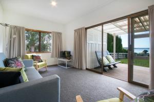 uma sala de estar com um sofá e uma porta de vidro deslizante em Hydrangea Cottage em Katikati