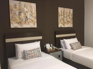 2 Betten in einem Hotelzimmer mit Gemälden an der Wand in der Unterkunft Chemara Boutique Hotel in Miri