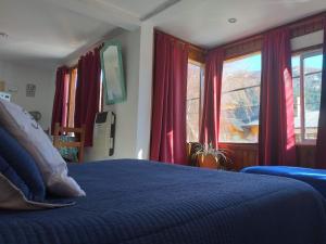 1 dormitorio con cama azul y cortinas rojas en Karma en San Martín de los Andes