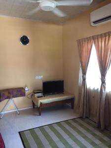 a living room with a tv and a window at AMIMAS HOMESTAY in Kampong Bagan Samak