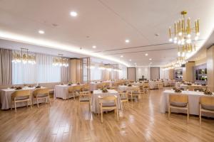 a dining room with white tables and chairs and chandeliers at Jin Jiang Pine City Hotel in Shanghai