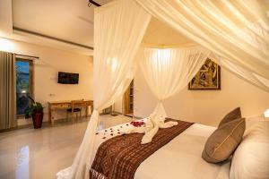 a bedroom with a bed with a canopy at Puri Sedana Ubud Villa in Ubud