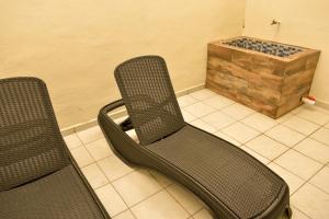 2 cadeiras sentadas num piso em azulejo com uma caixa de madeira em Casa Marisol em Cozumel