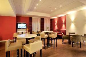 a restaurant with tables and chairs and a flat screen tv at Hotel Sachsen-Anhalt in Barleben