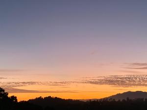 a sunset in the mountains with trees in the foreground at Casa Romance Escondido in Puerto Vallarta