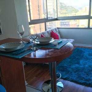 a table with two wine glasses and a couch at Depto Metro Santa Ana (2 dormitorios) in Santiago