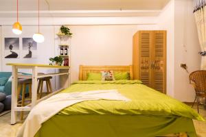 a bedroom with a green bed and a table at XiNing Chengxi ·Wanda square· in Xining