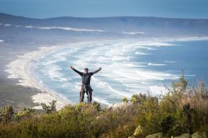 a man standing on top of a hill overlooking a beach at The Whale on Main B&B in Hermanus