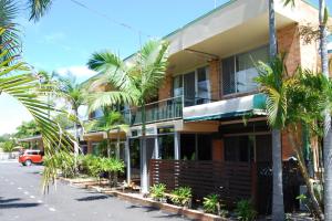 a building with palm trees in front of a street at Sunseeker Motel in Hervey Bay