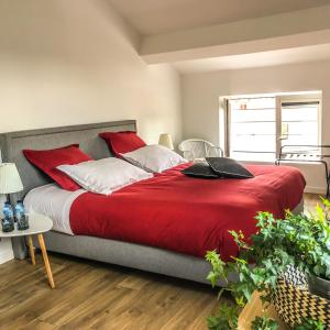 a bedroom with a large bed with red and white pillows at La Dormance in Beaune