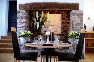 a table with glasses on it in front of a stone wall at Combe House Hotel in Holford