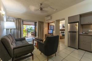 een woonkamer met een bank en stoelen en een keuken bij Southern Cross Atrium Apartments in Cairns