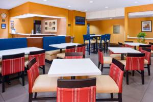 Comfort Inn and Suites Joplin في جوبلين: غرفة طعام مع طاولات وكراسي في مطعم