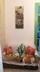 un divano bianco con cuscini rossi e un dipinto sul muro di Casa Cactus Sapiddu a Palermo
