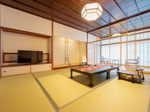 Habitación grande con mesa y TV de pantalla plana. en Jyoseikan, en Kochi