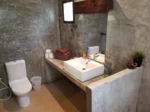 a bathroom with a sink and a toilet and a mirror at Baan Manali Resort in Thongsala