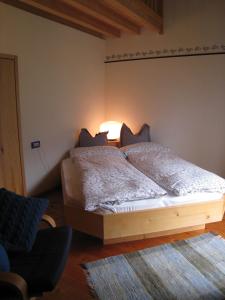 1 dormitorio con 1 cama, 1 silla y 1 lámpara en B&B Anna Maria, en Ledro