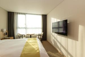 a hotel room with a bed and a flat screen tv at Hotel Winstory in Seogwipo