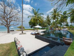 una piscina infinita en un complejo con el océano en el fondo en Villa Sapi by Elite Havens, en Tanjung