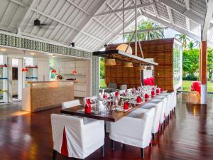 una sala da pranzo con un lungo tavolo e sedie bianche di Villa Sapi by Elite Havens a Tanjung