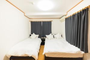 2 camas en una habitación con cortinas negras en Airstar Chiyo House x M&Z HOUSE en Fukuoka