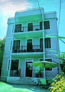 a building with chairs and an umbrella in front of it at Guest House Irakli in Makhinjauri