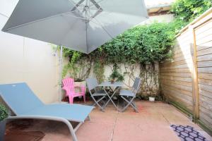une terrasse avec une table, des chaises et un parasol dans l'établissement Villa Hyper Centre, à Arcachon
