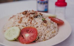 a plate of food with rice and a tomato at Poni Homestay 