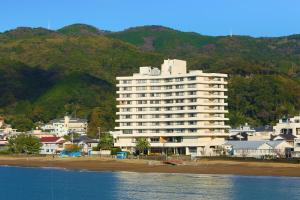 un gran edificio blanco en la playa junto al agua en Ooedo Onsen Monogatari Toi Marine Hotel, en Izu