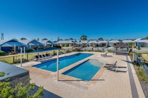 a swimming pool with chairs and umbrellas in a resort at Seafront Unit 60 in Jurien Bay
