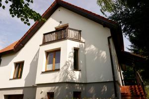 a white house with a balcony at Leśne zacisze in Rydzewo
