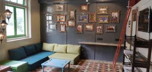 Hebbar's Heritage Home في مومباي: غرفة معيشة مع أريكة وصور على الحائط