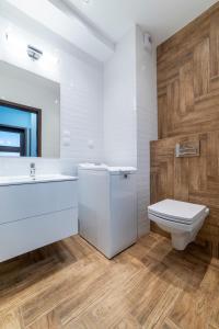La salle de bains blanche est pourvue de toilettes et d'un lavabo. dans l'établissement Apartament Jaskółcza 30, à Bydgoszcz
