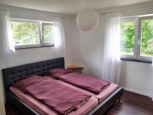 a bed in a room with two windows at Ferienwohnung Bella Casa in Öhningen