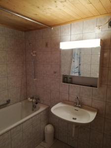 ein Badezimmer mit einem Waschbecken, einer Badewanne und einem Spiegel in der Unterkunft Wenz Wohnung in Schwarzsee