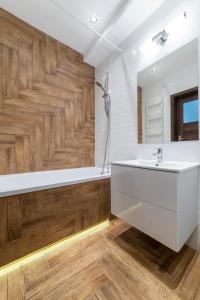 baño con lavabo blanco y pared de madera en Apartament Jaskółcza 30, en Bydgoszcz