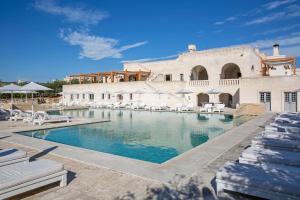 a swimming pool with chairs and a building at Borgo Egnazia in Savelletri di Fasano