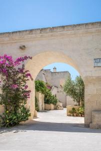 an archway with a building in the background with purple flowers at Borgo Egnazia in Savelletri di Fasano
