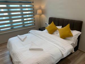 een groot wit bed met gele kussens en een raam bij SweetHome 3BR@P'Residence Apartment 1226Sft 6 in Kuching