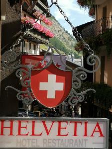 um sinal para um hotel com uma bandeira suíça em Petit Helvetia Budget Hotel em Zermatt
