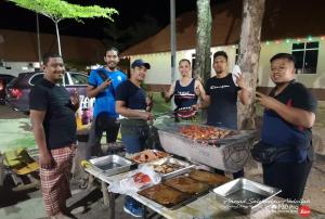een groep mannen die rond een barbecue staan bij Marang Village Resort in Marang